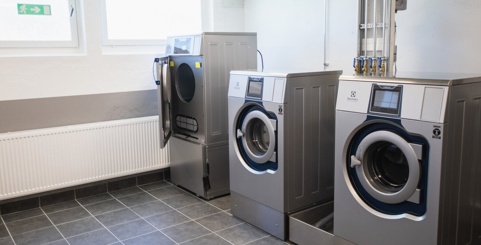 Bild på nya tvättmaskiner och torktumlare i tvättstugan på Ågatan 44 efter renovering.